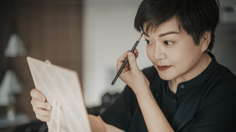 Woman applying eyebrow pencil