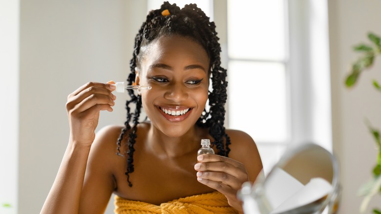 Smiling woman applying eye serum