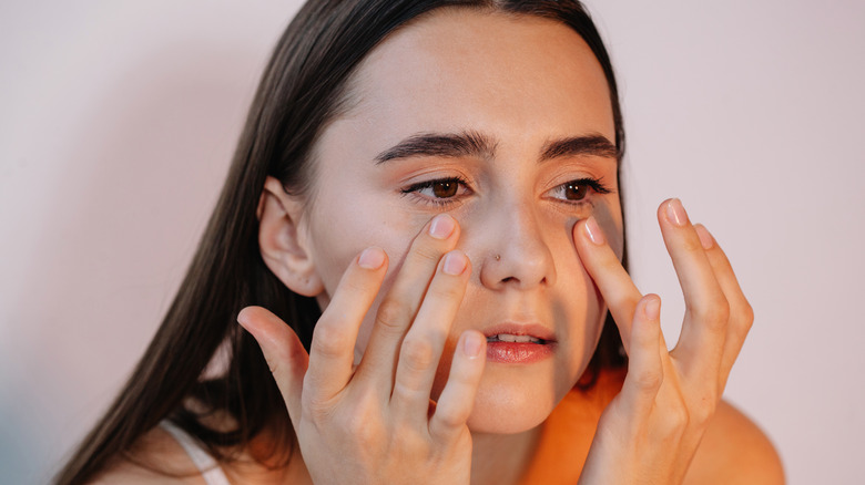 Young woman examining eye area