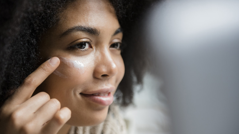 Woman applying sunscreen under eyes