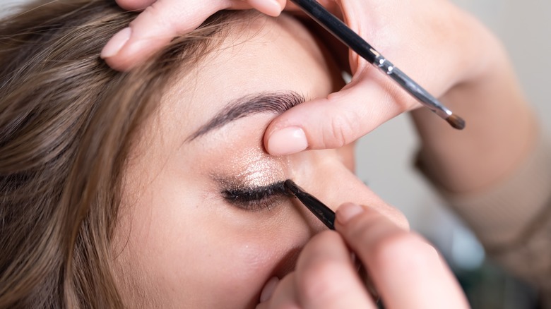 woman getting eyeliner applied