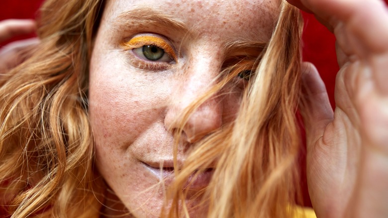 Closeup of a woman wearing orange eyeliner.