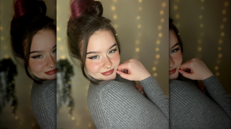 Woman poses wearing messy bun with loose tendrils 