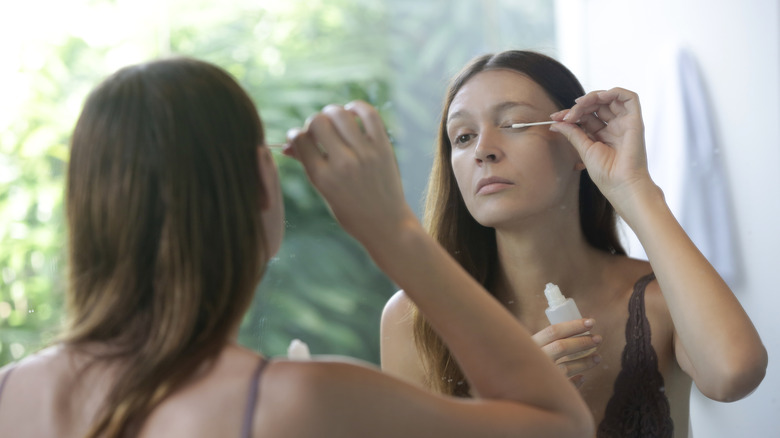 Woman applying oil to lashes