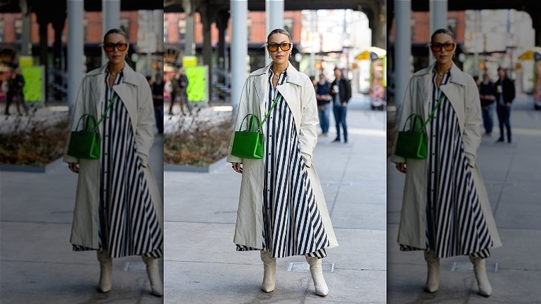 Person in green trench coat and midi dress