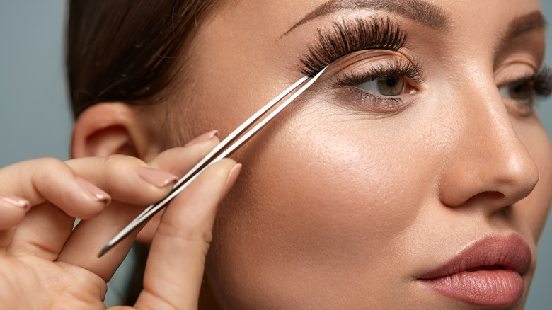 woman applying false lashes with tweezer