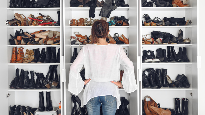 Woman looking at closet with many pairs of shoes