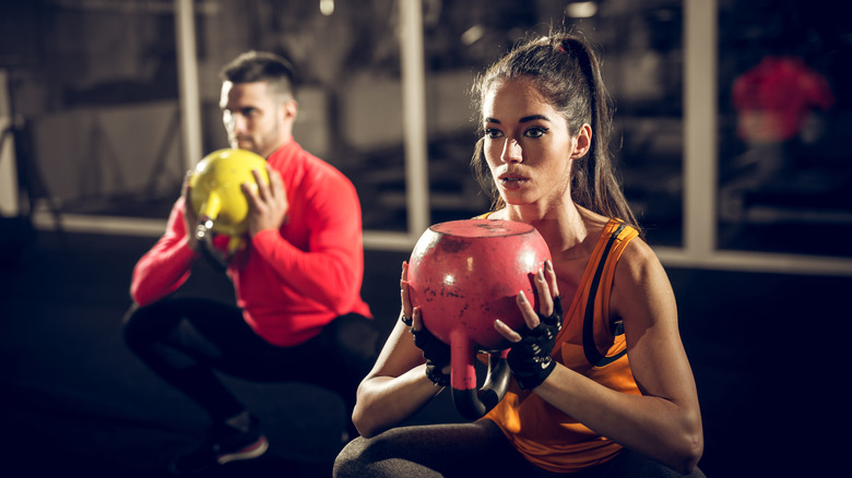Man and woman squatting with kettlebells