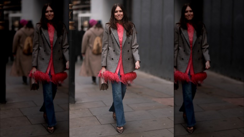 Woman wearing feather-trimmed blazer, jeans