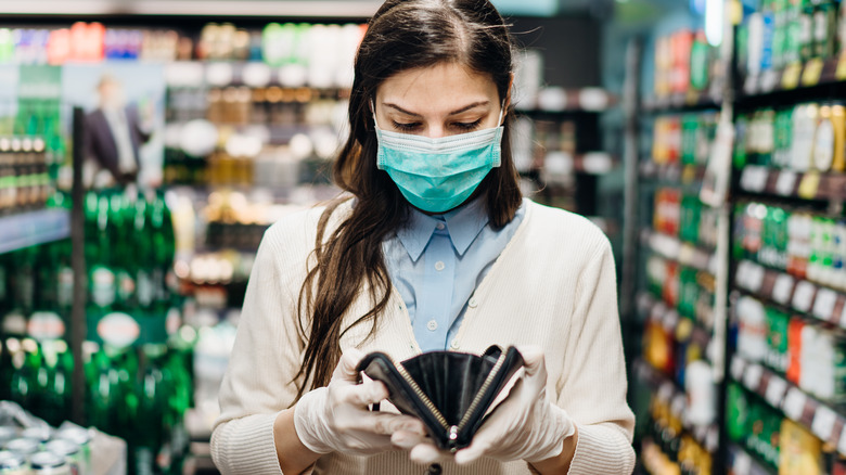 Woman looks at empty wallet in store