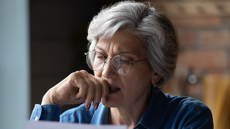 Older model looking at paper with concerned expression