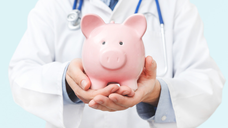 Doctor holding a pink piggy bank