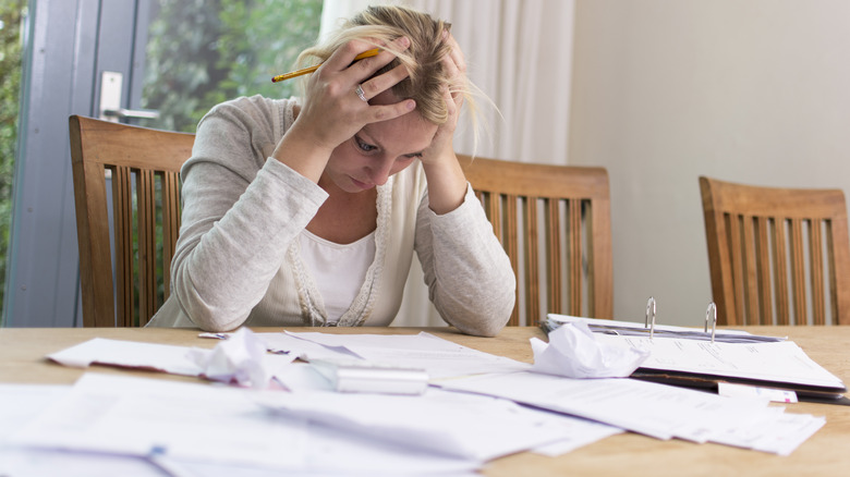 Woman stressed with table covered in paperwork