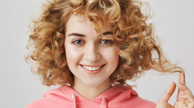 Woman smiling while playing with curls