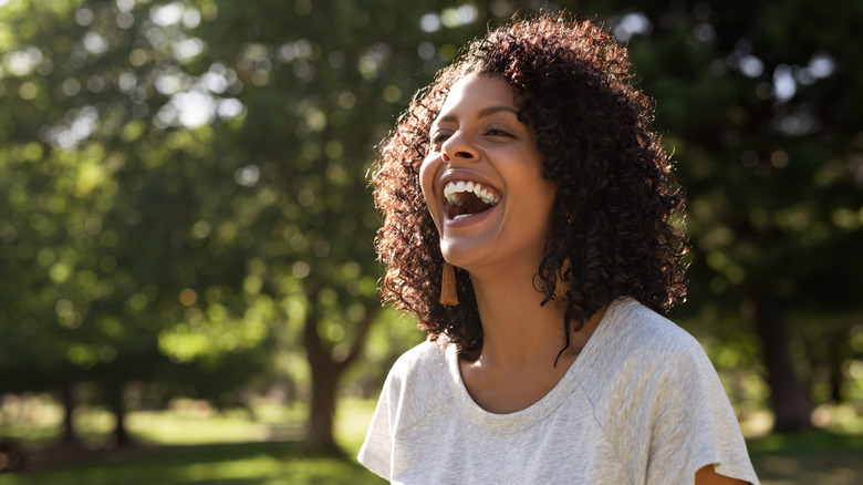 Woman with curly hair smiling in park