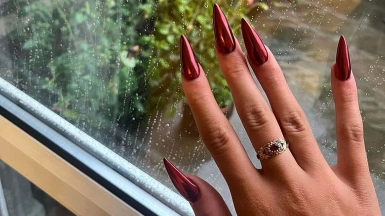 Hand displaying stiletto red chrome nails