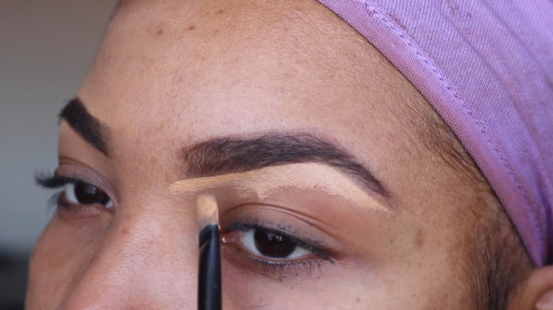 Woman applying concealer on eyebrows