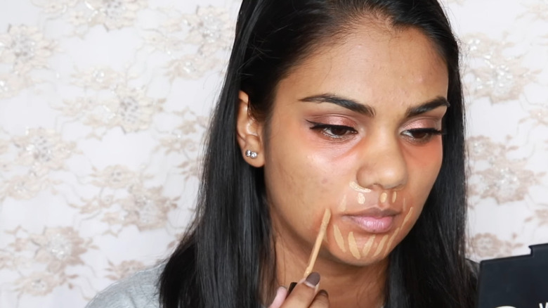 Woman applying concealer around mouth