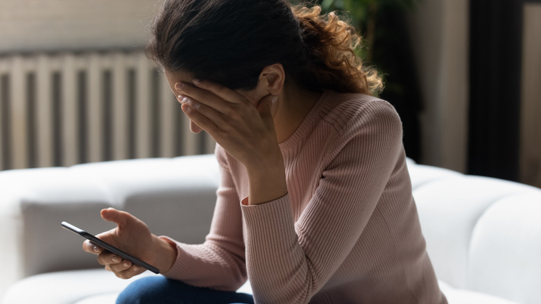 sad woman holding her phone