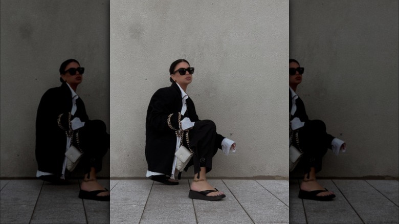 woman wearing black pants, blazer, flatforms and white top