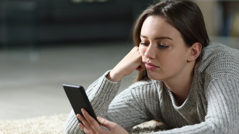 Woman using phone on floor