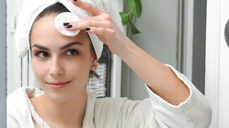 Woman cleansing forehead with cotton pad