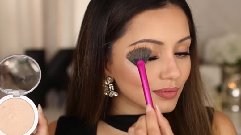 woman applying highlighter to brow