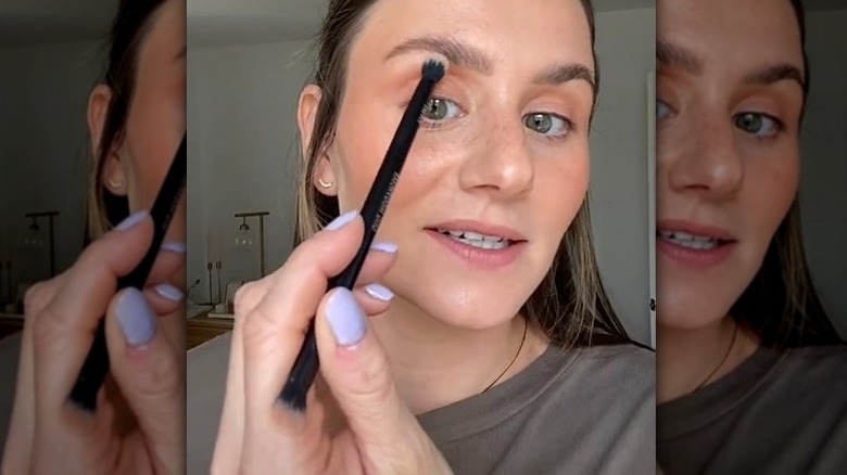 woman applying highlighter to brow