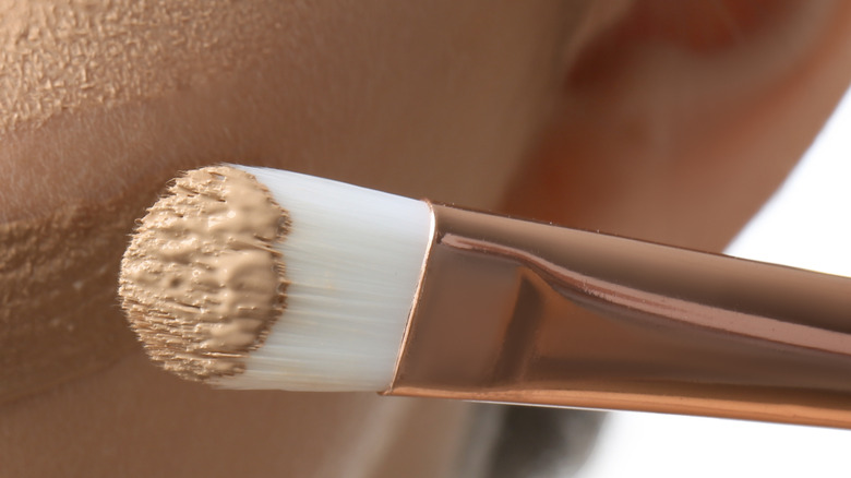 synthetic brush applying concealer to skin