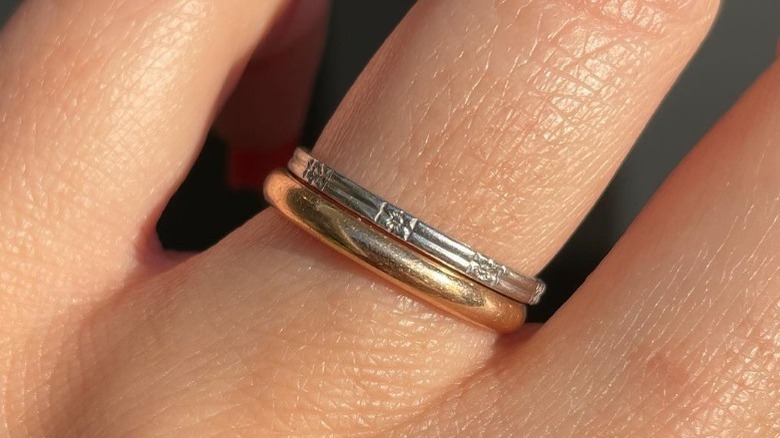 Finger wearing one yellow and one white gold ring