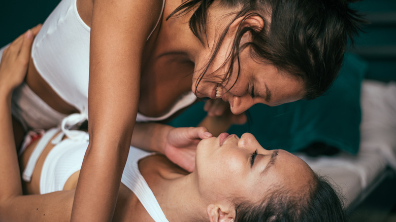 Lesbian couple smiling in bed