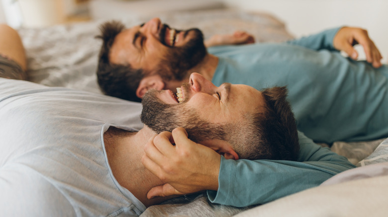 Gay couple smiling in bed