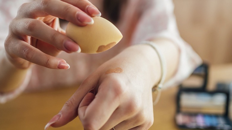 Woman applying foundation on back of her hand