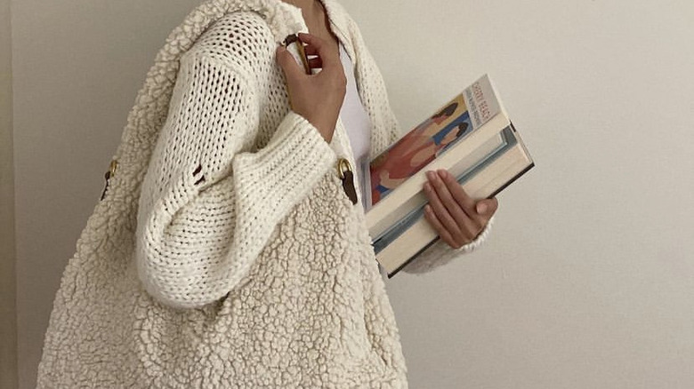 woman holding hobo bag and books