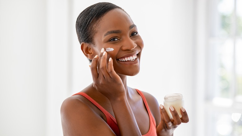 smiling woman applying skin cream