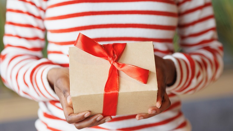 Close up of woman holding gift with red ribbon