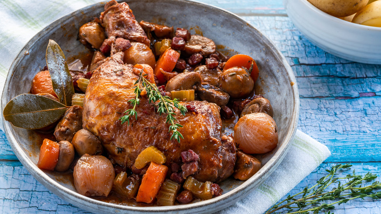 Bowl of coq au vin served with fresh thyme sprigs