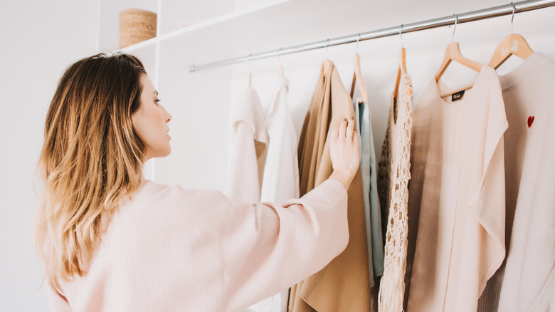 Woman choosing outfit from clothes rack