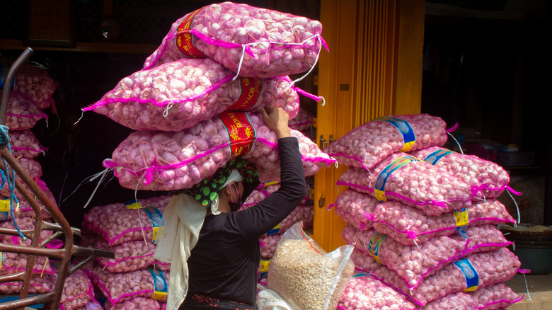 woman carries bags of garlic