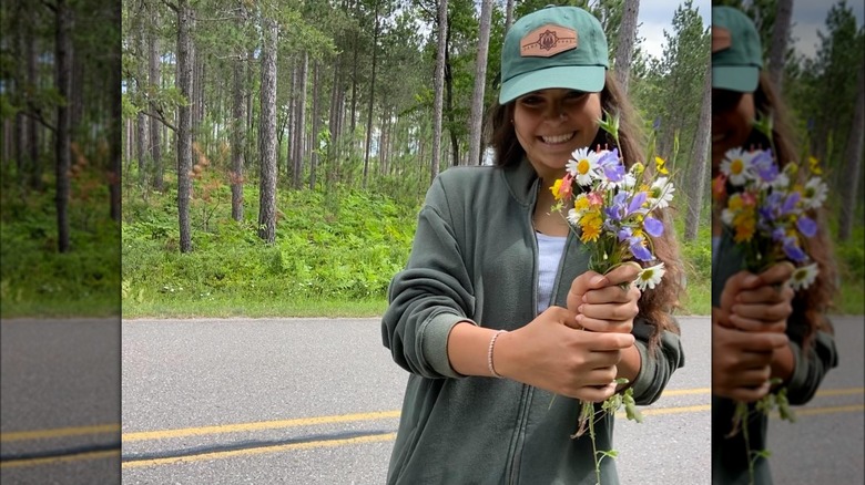 Woman wearing baseball cap, holding flowers