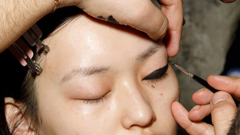 makeup artist applying eyeliner