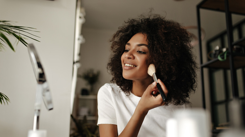 woman applying makeup with brush