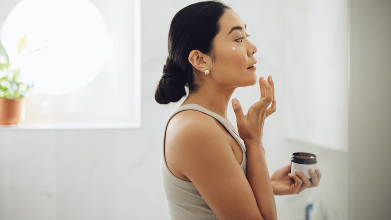 Woman moisturizing in bathroom