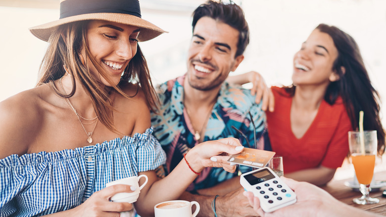 Friends smile as woman pays bill