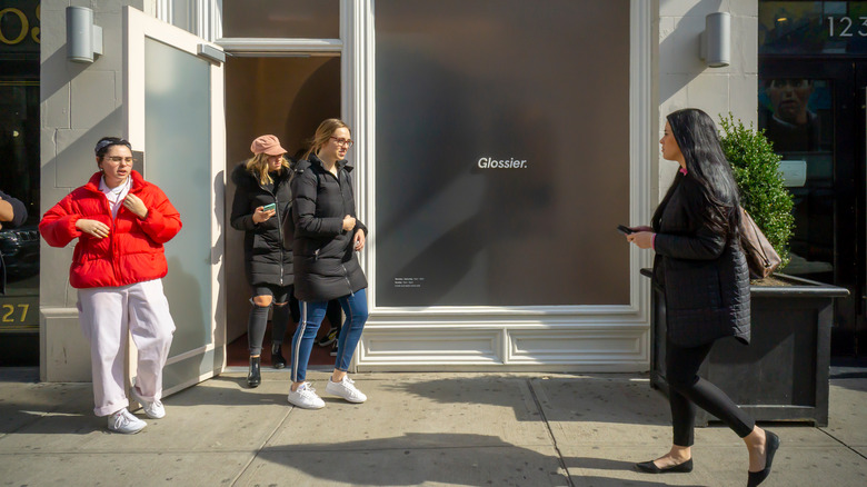 Four people outside a Glossier store