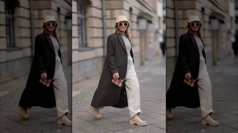 Woman outdoors wearing coat, bucket hat, sweatpants 