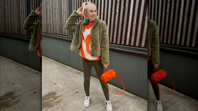 Woman poses with orange purse 