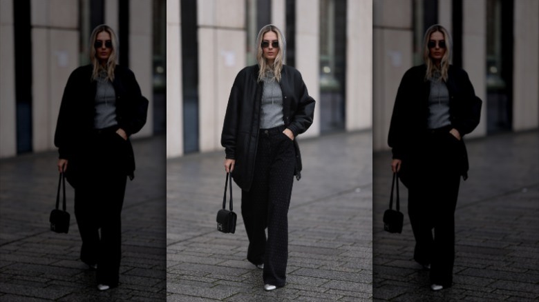 woman wearing silver top and black jacket, jeans