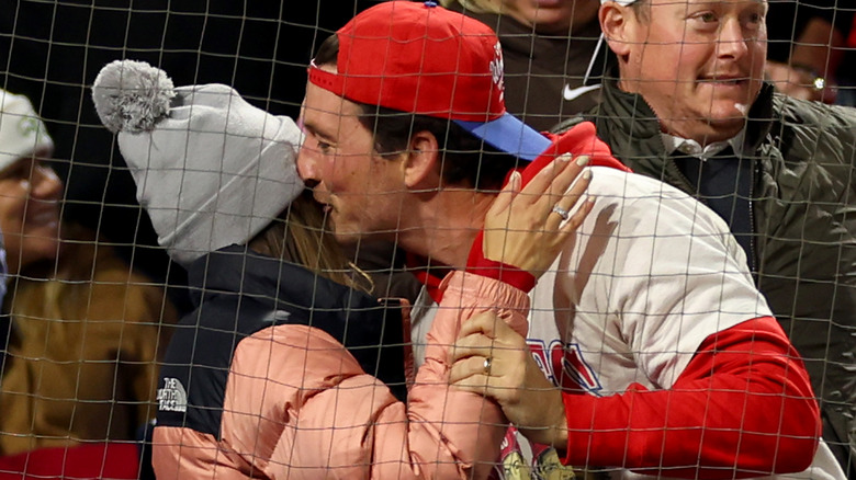 Miles Teller giving Keleigh Sperry a kiss during a sports game.