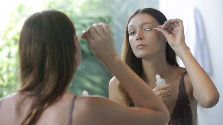 woman applying serum to eyelashes